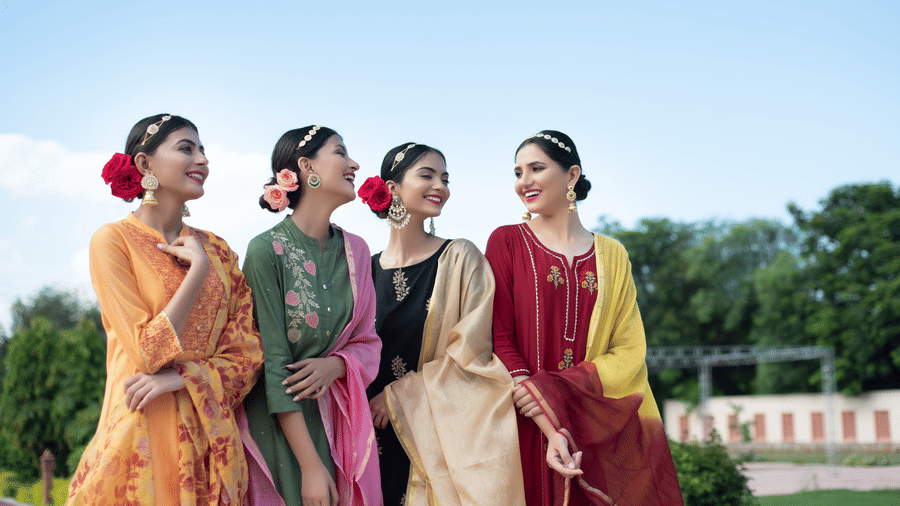 Bridesmaids in colourful traditional outfits enjoying an outdoor wedding celebration.