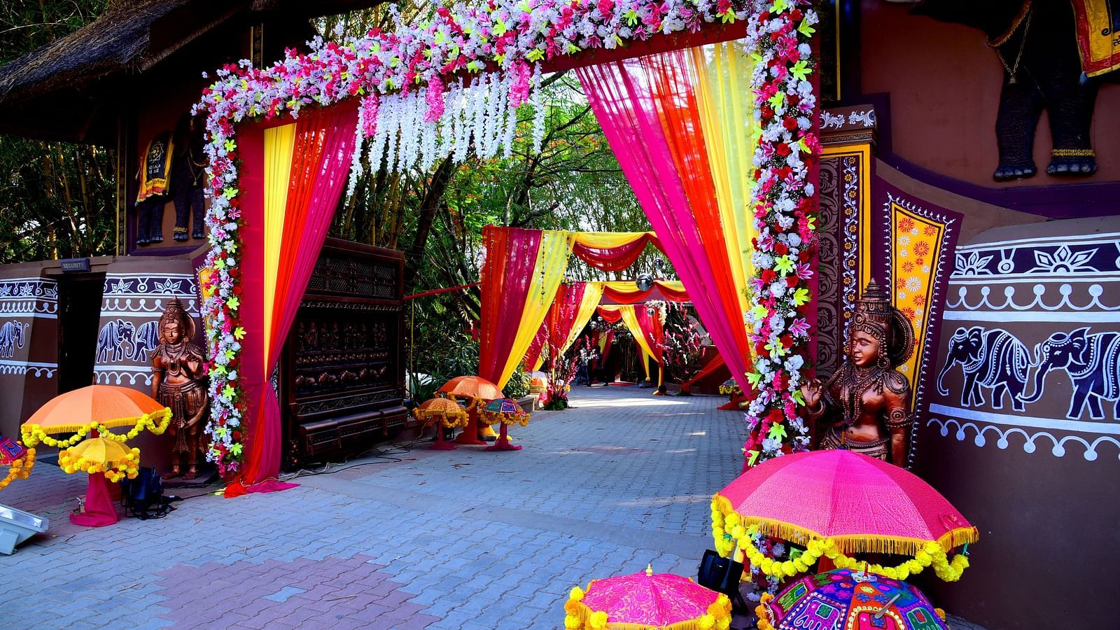 image of a grand entrance for a wedding decorated with flowers and drapes at hoysala village resort in hassan