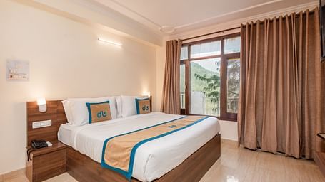 Image of a room featuring a king size bed with a side table, marble flooring and an expansive window | DLS Anupam Resort, Dharamshala