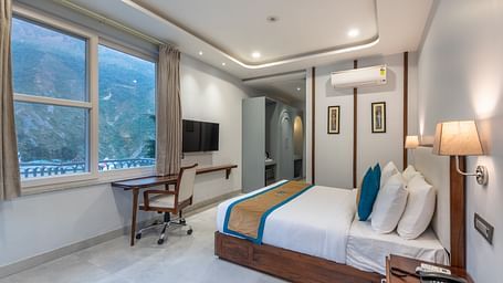 Spring Suite at DLS Spring Valley Resort Dharamshala featuring a kind bed, work desk and chair and ambient lighting from the window