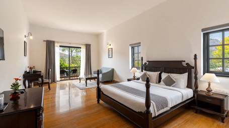 A double bed with a wooden frame along with bed sides tables on its either sides at Hunting Suite With Common Cloud Pool &amp; Terrace at The Hunting Lodge, Udaipur.