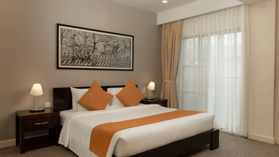Penthouse bedroom at Central Mansions, Phnom Penh with a king bed, bedside tables, and large windows.