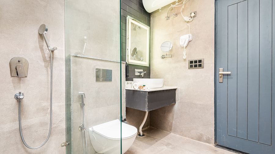 Bathroom of Luxury Cottage at DLS Divine River Resort and  Spa featuring shower, sink area, mirror and a toilet.