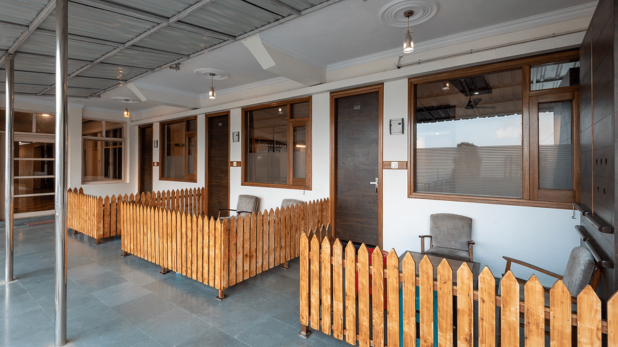 Common balcony with wooden fencing and chairs in front of room doors - DLS Meghavan Resort, Dharamshala