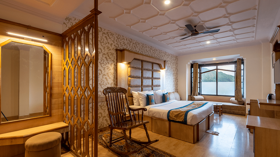 A premium room near Bhagsunag waterfall with elegant wooden decor, a cosy bed, seating area, TV, and stunning mountain views, offering a relaxing ambience - DLS Meghavan Resort, Dharamshala