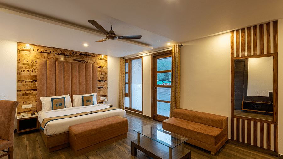 A stylish premium room with a large bed, modern furniture, and mountain views, offering a cosy and relaxing atmosphere - DLS Meghavan Resort, Dharamshala