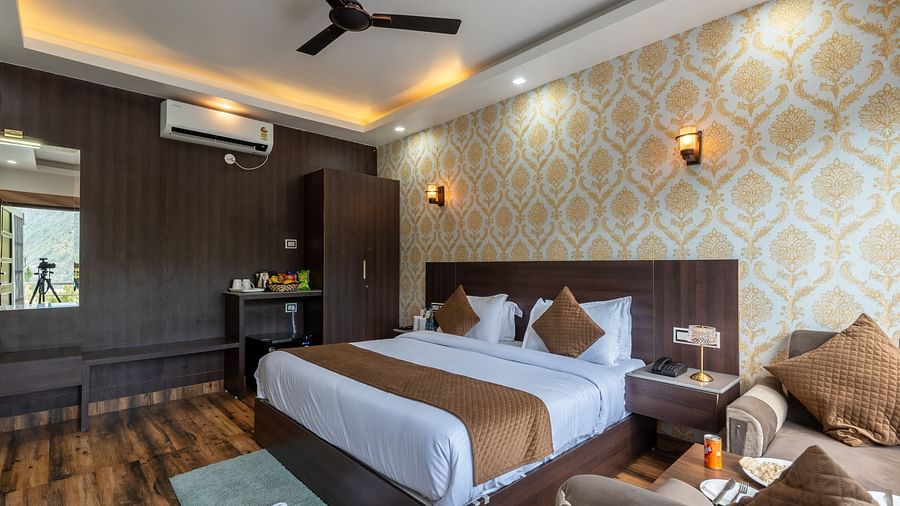  Stylish hotel room with a king size bed, decorative wallpaper, wooden flooring, ceiling fan, and a cosy seating area with refreshments - DLS Nature Trinket Resort, Dalhousie. 