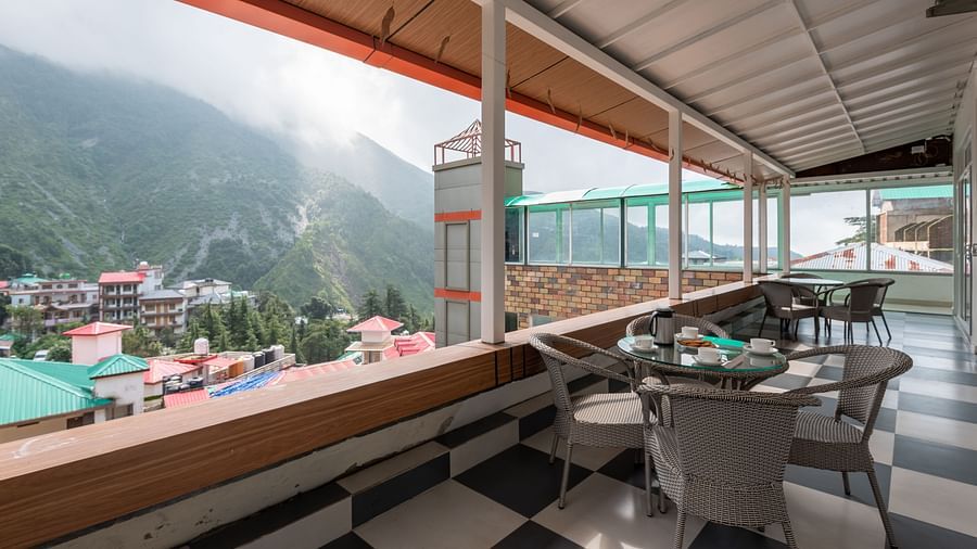 Balcony area at at DLS Spring Valley Resort Dharamshala featuring chairs and tables with a beautiful view 
