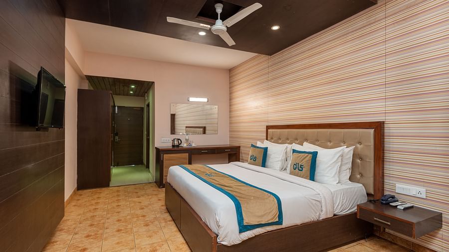 Overview of Deluxe Non view room at DLS Spring Valley resort  Dharamshala featuring a  king bed, table, chairs and a TV