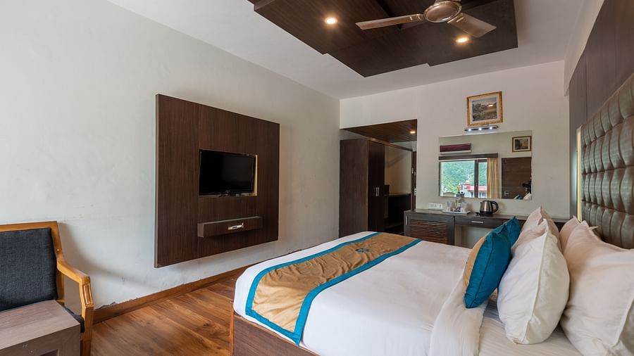 A Premium Room at DLS Spring Valley Resort Dharamshala featuring a king size bed, TV and a chair