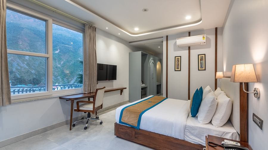 Spring Suite at DLS Spring Valley Resort Dharamshala featuring a kind bed, work desk and chair and ambient lighting from the window