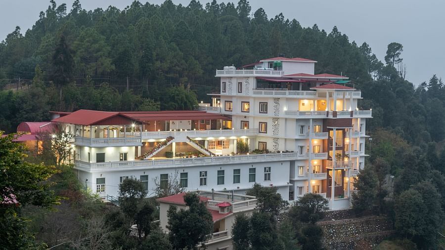 Exterior view of DLS Tehri Club Resort nestled amidst lush green hills.