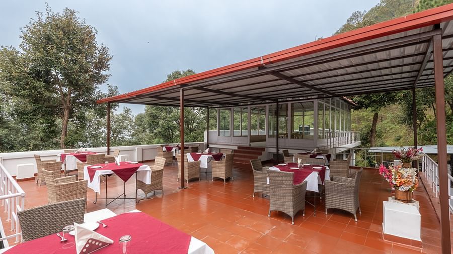 Image of the open air restaurant at DLS Tehri Resort with chairs and tables arranged.