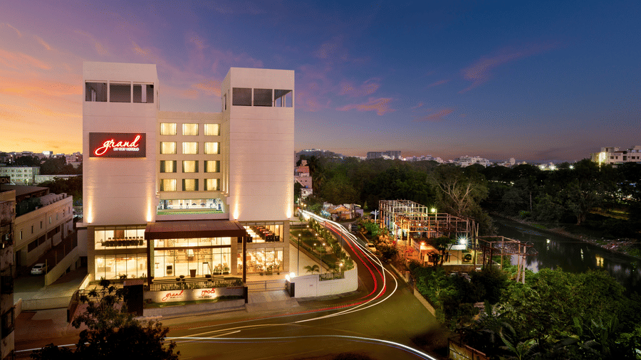 Facade image of our 5-star hotel in Vijayawada at night surrounded by green foliage | Grand Vijayawada by GRT Hotels