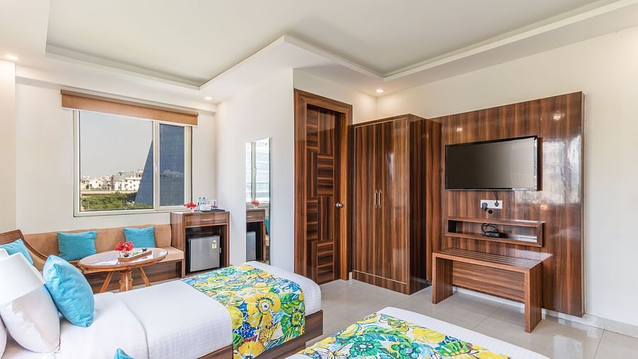side view image of Deluxe Twin Room featuring twin beds, sofa and a TV | Inde Hotel Cyber City