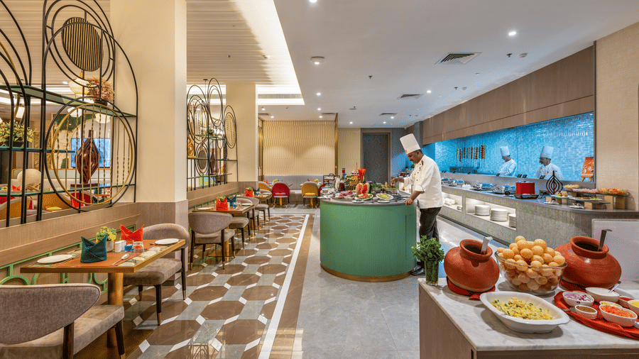 Restaurant buffet counter with a striking green accent and blue tiled wall at Lords Inn Somnath, offering a fresh dining experience.