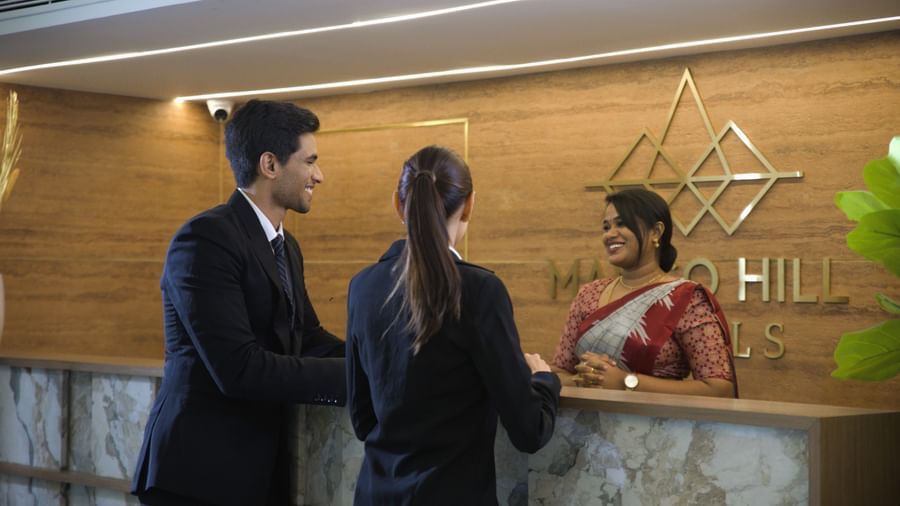 Reception staff at Mango Hill Central Chennai welcoming guests with a warm smile at the front desk.
