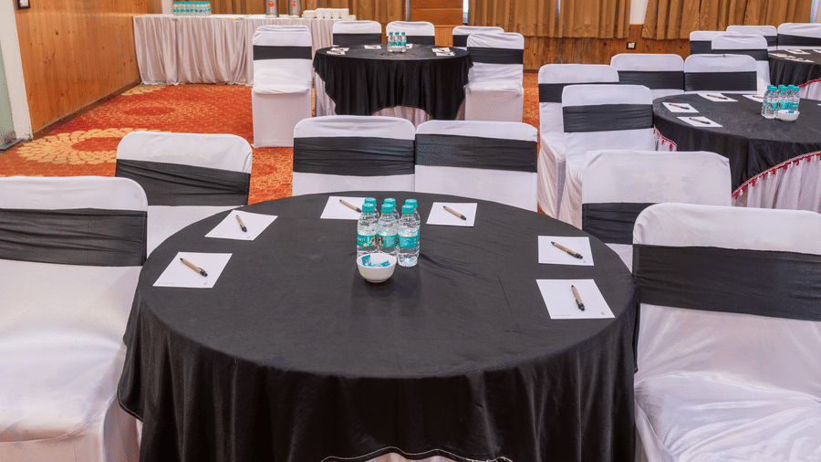 A table with water bottles, pens and papers and surrounded by chairs at DLS Hotels On The Ganges.