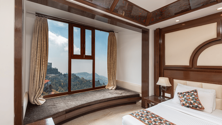 Cosy seating alcove with wide window overlooking hills at The Solitaire Resort, offering a charming corner for guests to relax and enjoy picturesque scenery.