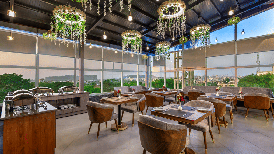 Elegant PDR bar lounge with round tables, wooden decor, and hanging light fixtures.