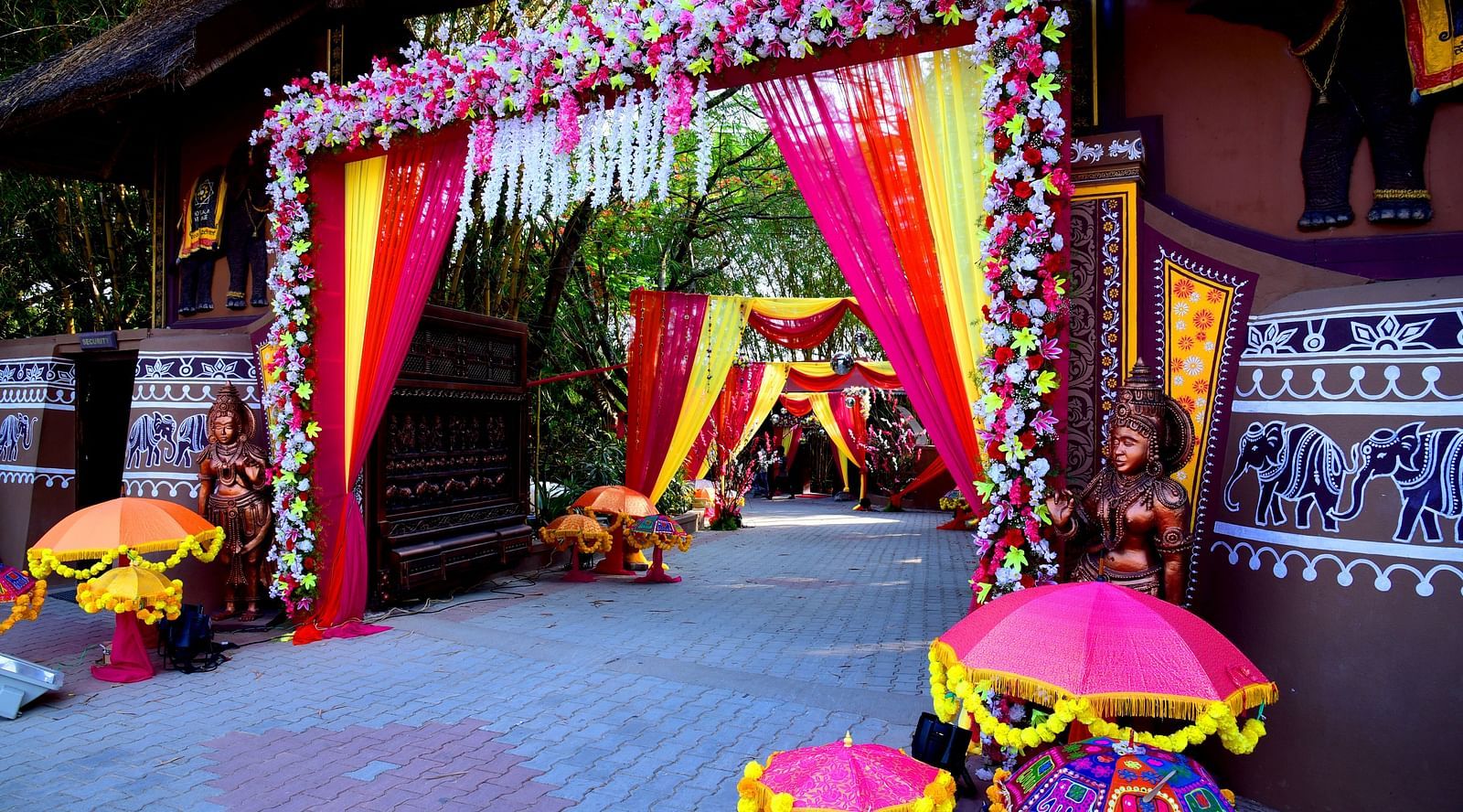 image of a grand entrance for a wedding decorated with flowers and drapes at hoysala village resort in hassan