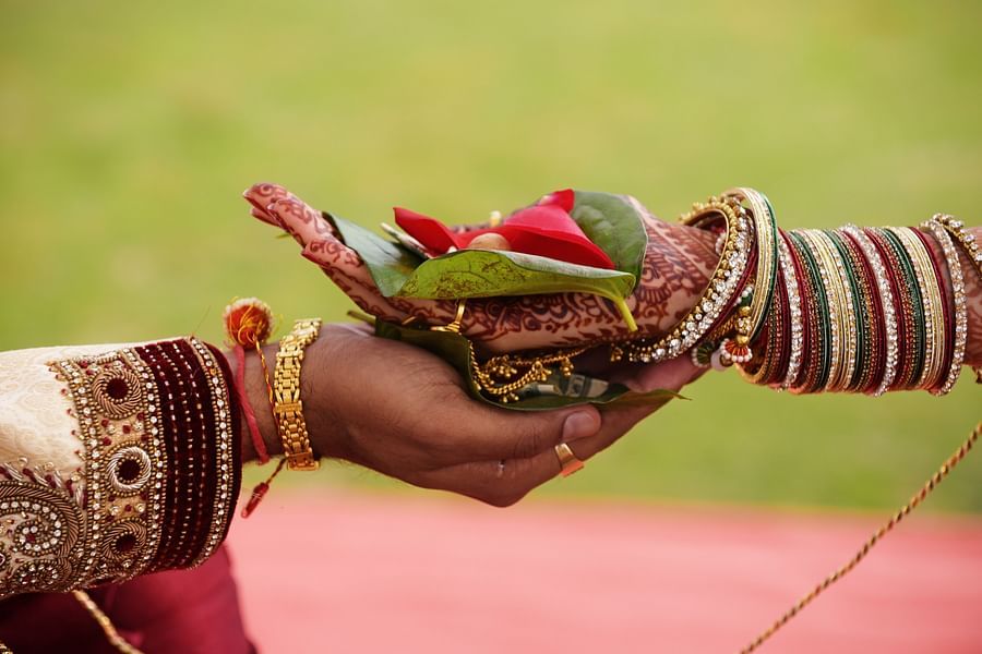 bride and groom holding hands with flowers for wedding ritual