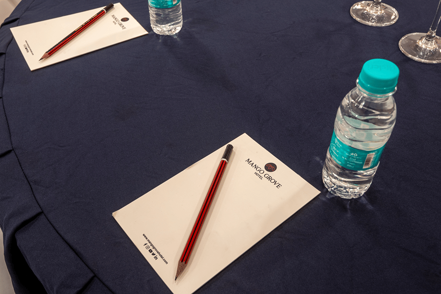 Conference table setup with notepads, pens and water bottles arranged for delegates at a meeting at Mango Grove Hotel.