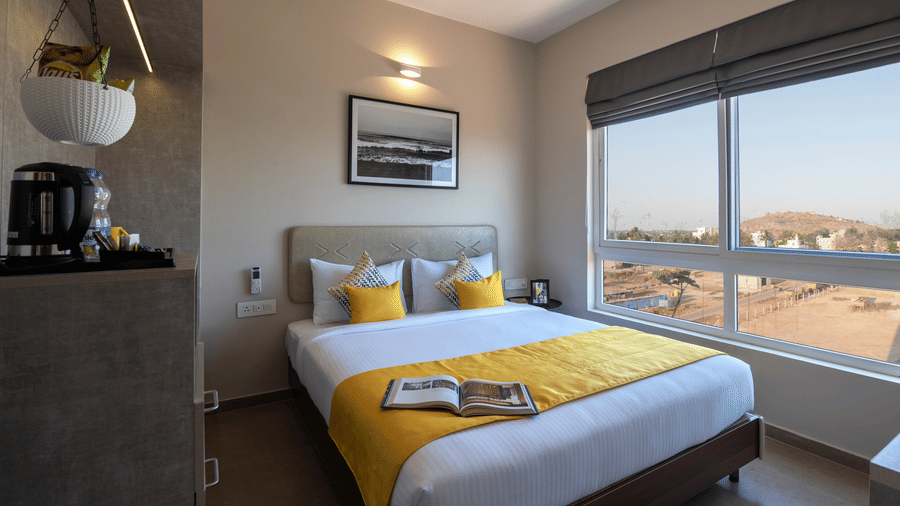 Spacious deluxe room with a large bed, modern interiors, and window view at Avora Tree, a hotel near Bangalore International Airport ideal for comfortable airport stays.