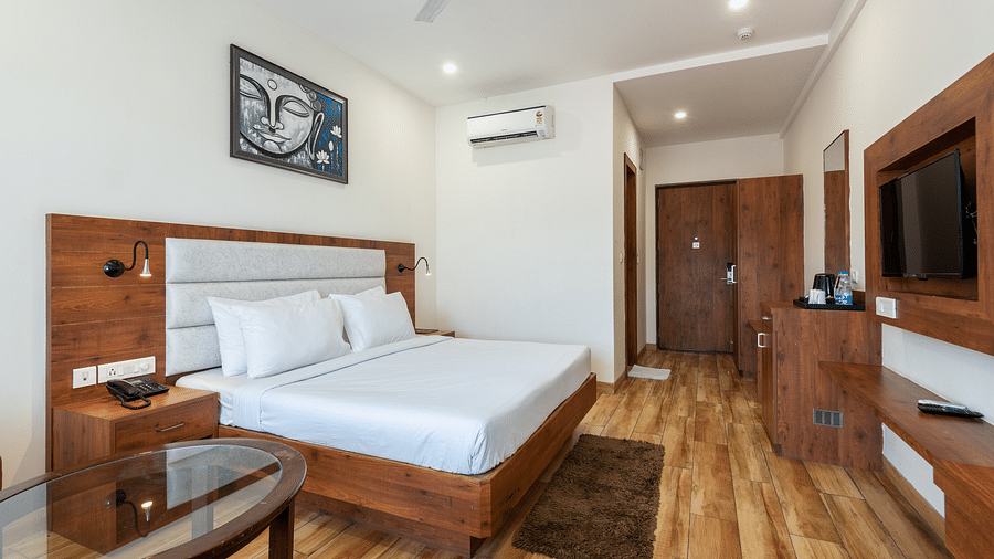 Premium room featuring a tea and coffee maker, air-conditioning, and a Buddha portrait above the bed at DLS The Classio