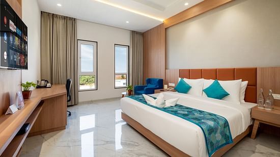a double bed with blue runner and side tables inside one of the Rooms - The Orchid Hotel, Jamnagar