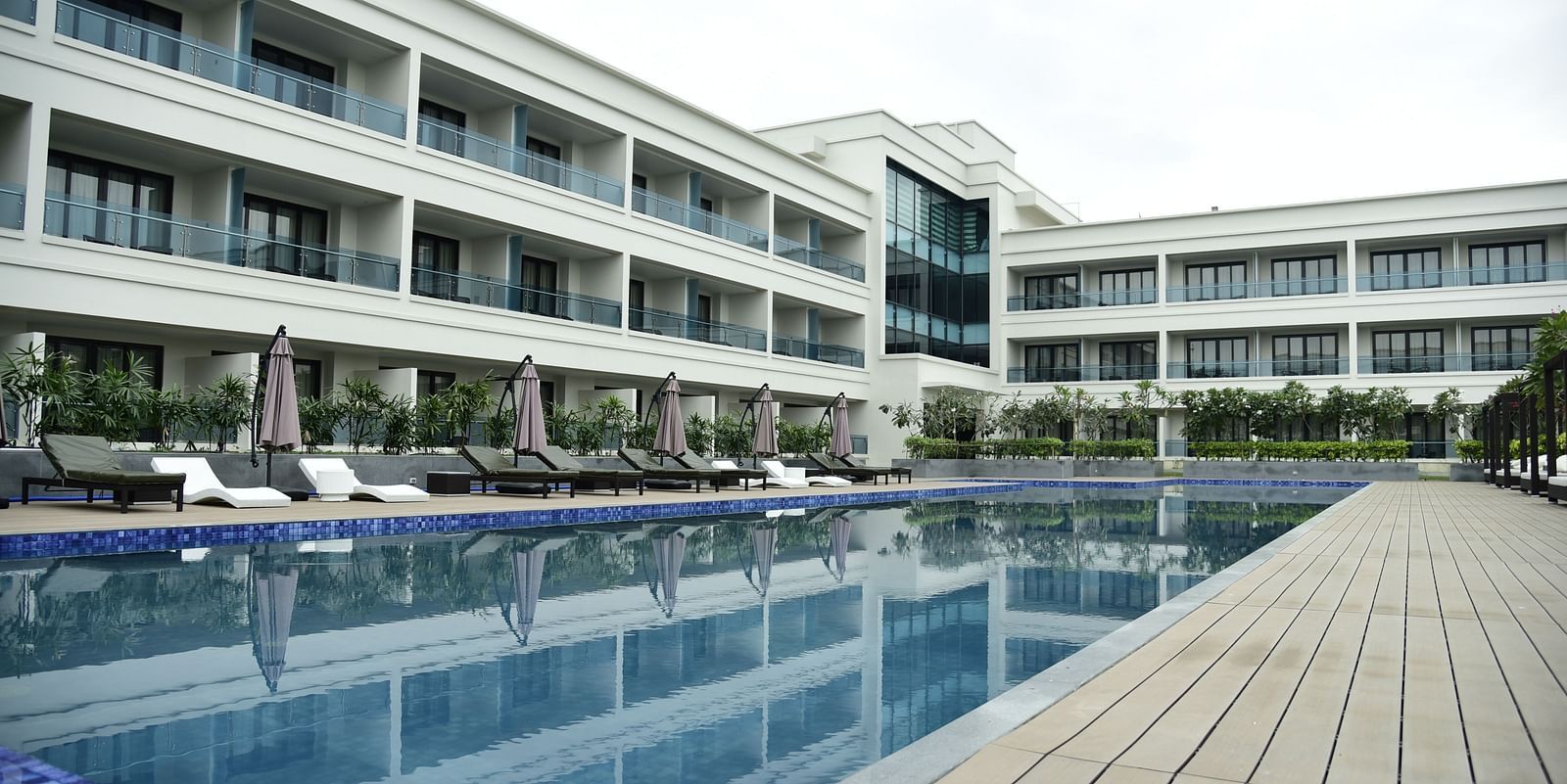 A facade view of the hotel, with the reflection of the building in the swimming pool