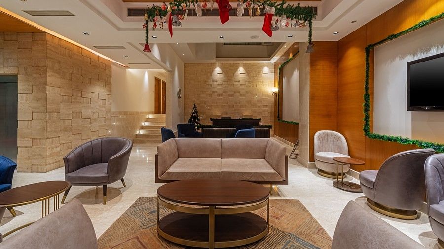A front view of a reception seating area with sofas, table, carpet, Christmas decor and soft lighting at Hotel Saket 27, New Delhi