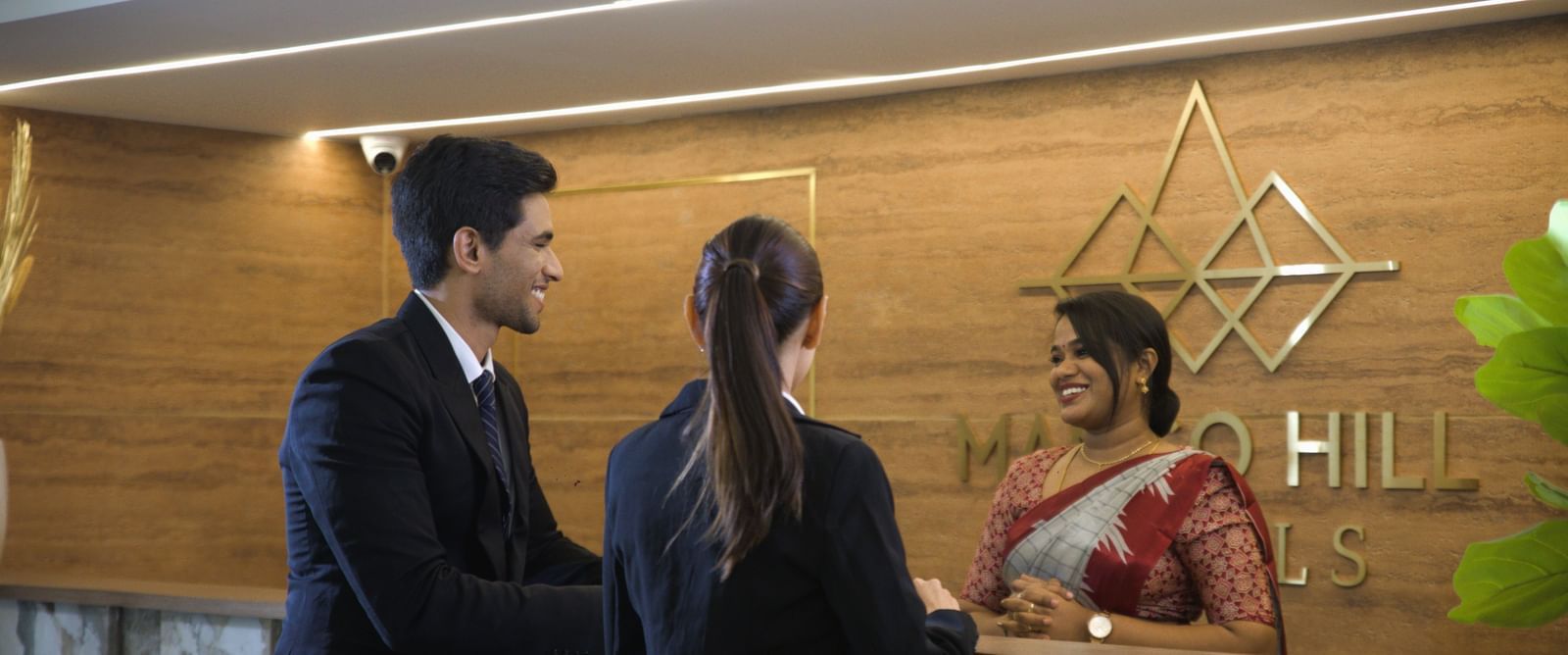 Reception staff at Mango Hill Central Chennai welcoming guests with a warm smile at the front desk.