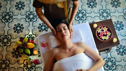 A masseuse providing a massage to a woman who is lying face up