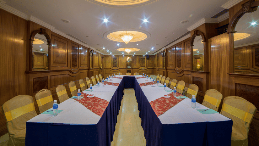A seating area at a conference hall at Raj Park Hotel in Chennai, with chandeliers, chairs, and tables set up for an event.