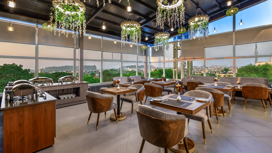 Elegant PDR bar lounge with round tables, wooden decor, and hanging light fixtures.