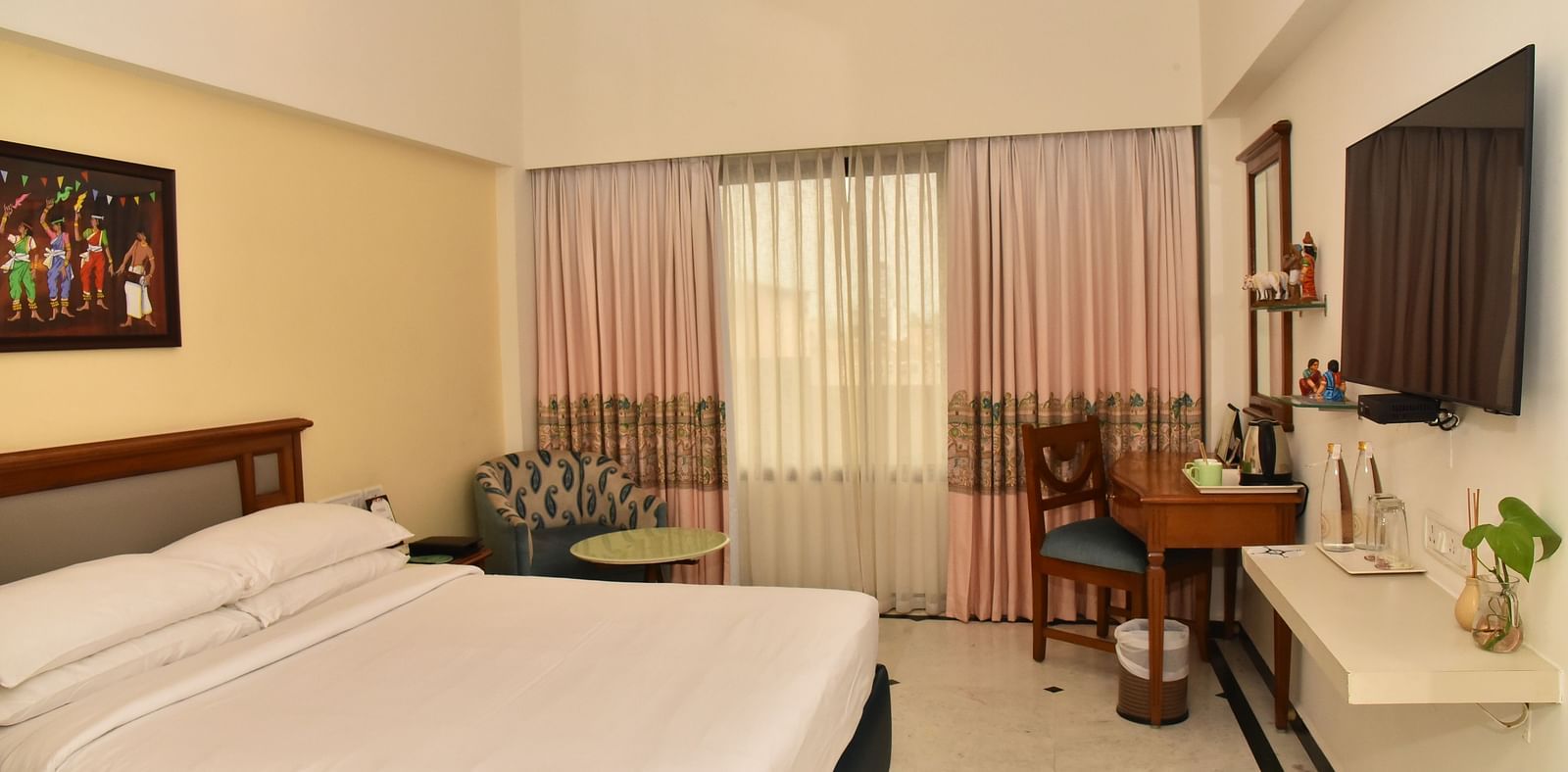 An image of our Deluxe Room featuring a large bed positioned in front of a wall-mounted television - Regency Kanchipuram by GRT Hotels