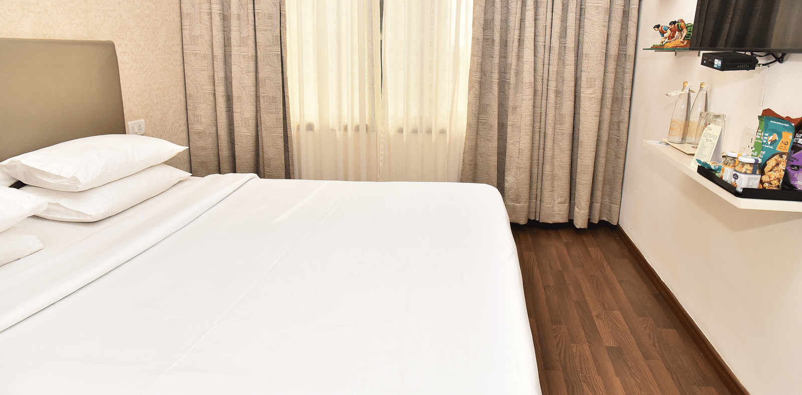 An image of a bedroom in our suite in Kanchipuram, with a large bed positioned in front of a wall-mounted television - Regency Kanchipuram by GRT Hotels