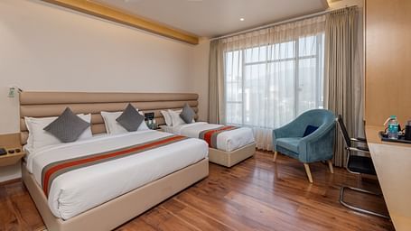 An image featuring a room with two beds, two chairs, a work desk and a window - DLS Hotel Arihant, Haridwar