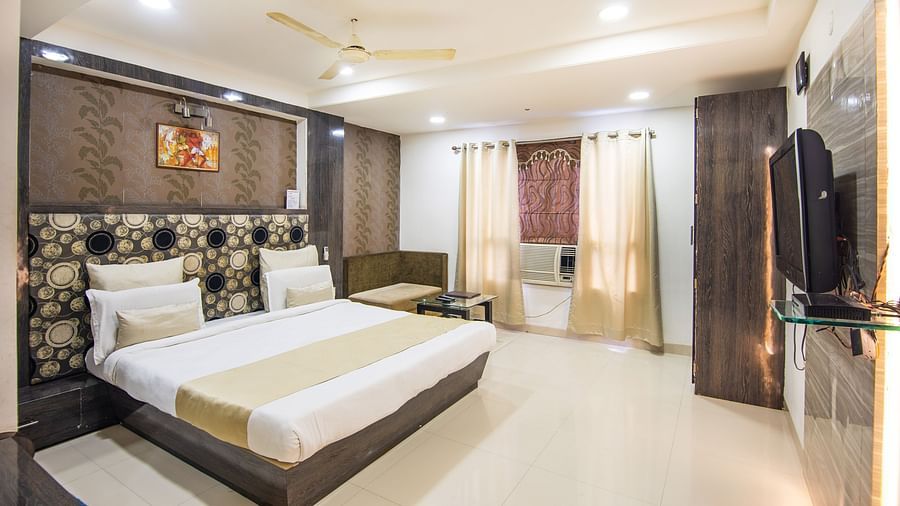 A room with a beautiful bed, a wall-painting sofa, a couch bed, a TV and a coffee table - Hotel Morya, Bhopal