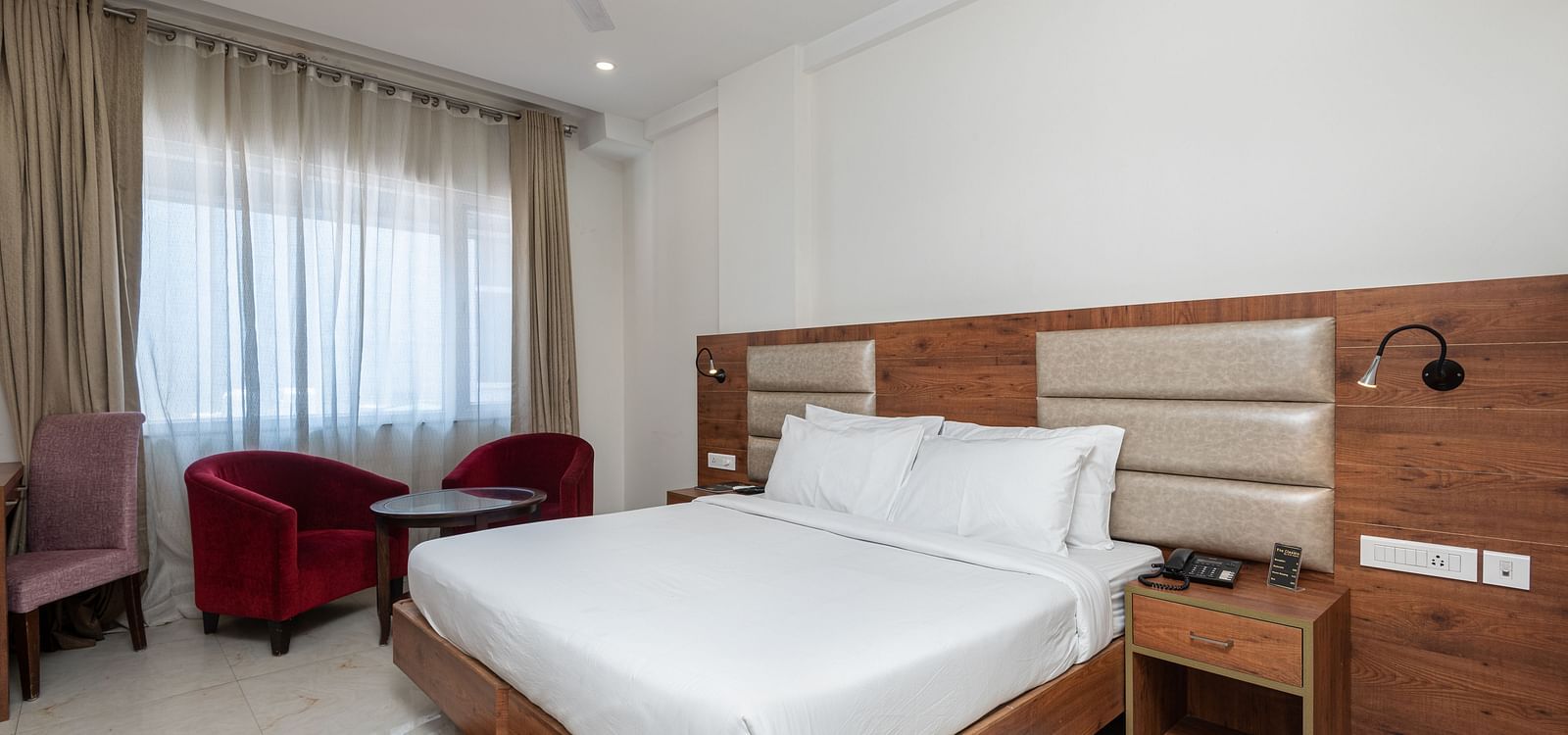 Premium room with a king size bed featuring a stylish headboard, and a window adorned with a soft sheer curtain at DLS The Classio
