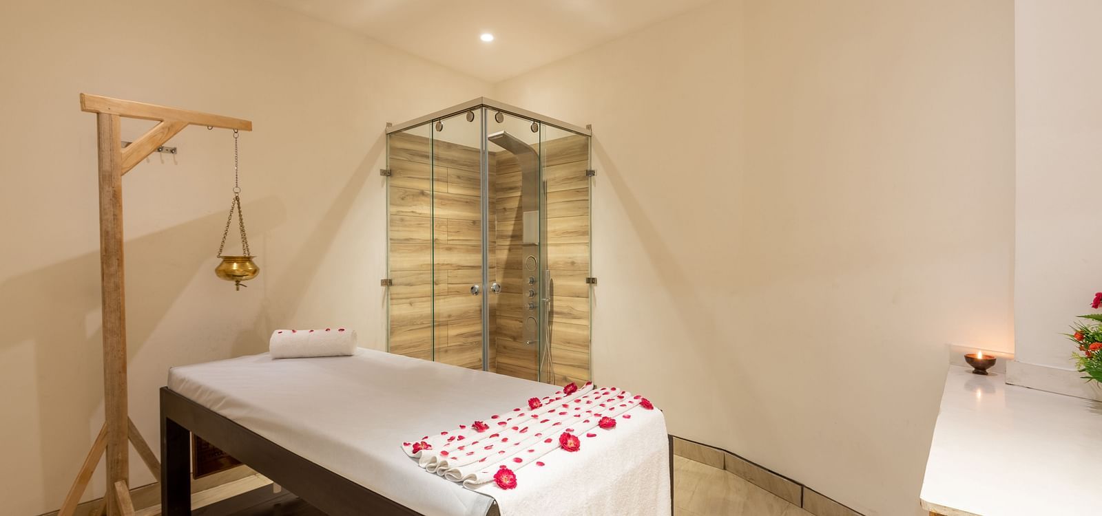 side view of spa with a bed decorated with rose petals and a Shirodhara vessel hanging from a stand at DLS The Classio
