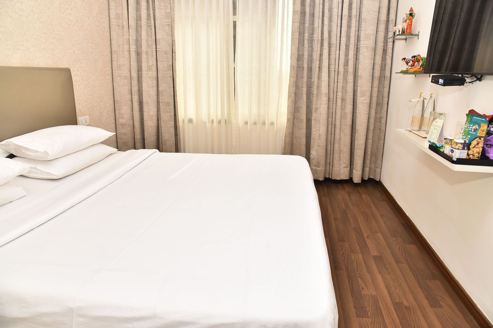 An image of a bedroom in our suite in Kanchipuram, with a large bed positioned in front of a wall-mounted television - Regency Kanchipuram by GRT Hotels