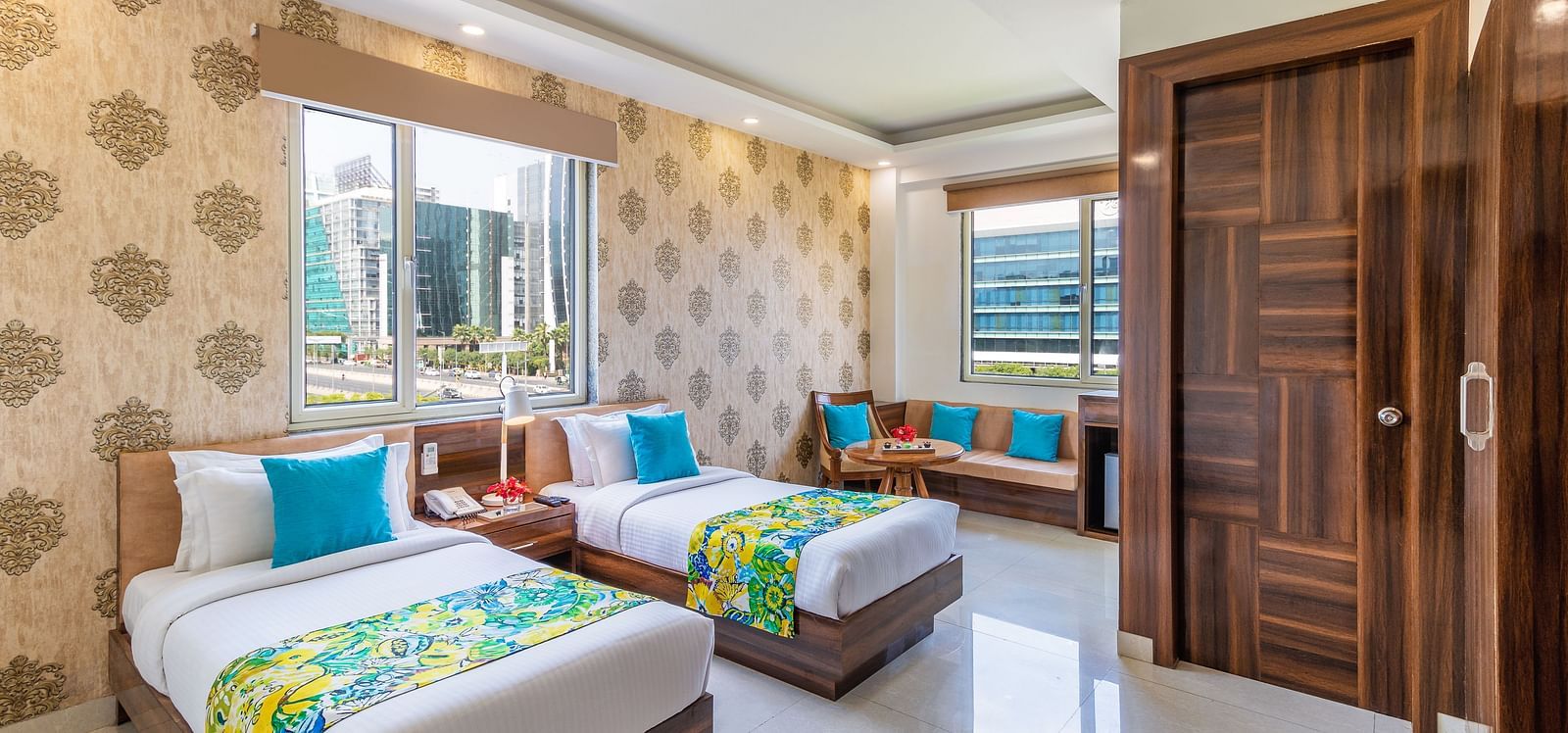 side view image of Super Deluxe Twin Room featuring twin beds, sofa, window and a TV | Inde Hotel Cyber City