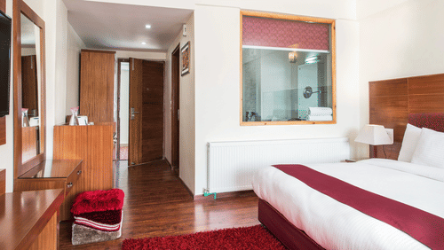 Side view of a room with a bed and a large mirror in front at Hotel Singge Palace.