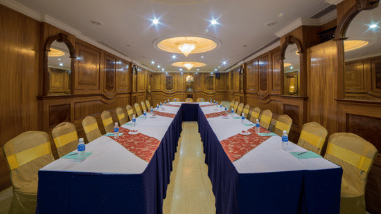 A seating area at a conference hall at Raj Park Hotel in Chennai, with chandeliers, chairs, and tables set up for an event.