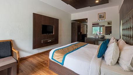 A Premium Room at DLS Spring Valley Resort Dharamshala featuring a king size bed, TV and a chair