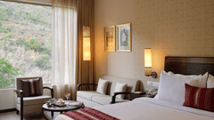 Premium Room at Marasa Sarovar Premiere, Tirupati featuring a king size bed, cosy seating area, large window with scenic hillside views, and warm contemporary interiors.