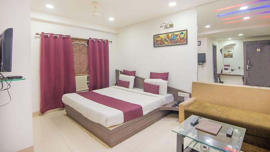 A room with a well made bed, a sofa cum bed, a wall painting and a coffee table - Hotel Morya, Bhopal