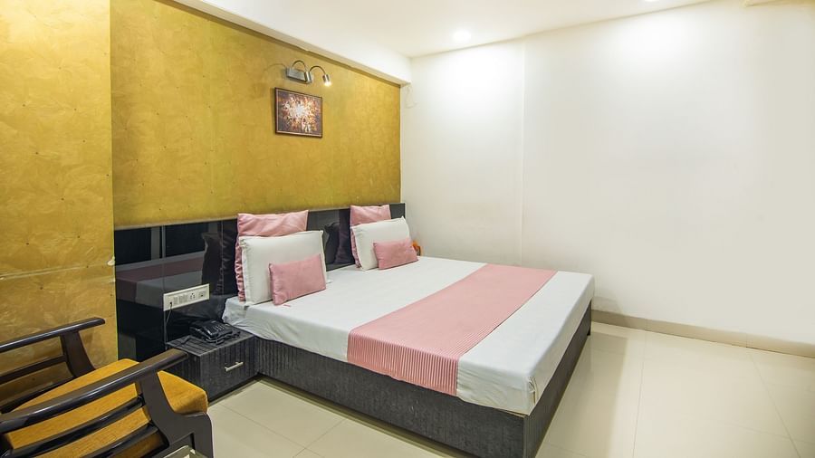 A room with golden wall paper, a sofa chair, a side drawer and a wall painting  -  Hotel Morya, Bhopal